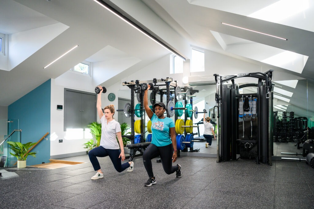 Physiotherapist demonstrating exercises to patient undergoing ACL Rehabilitation in a gym