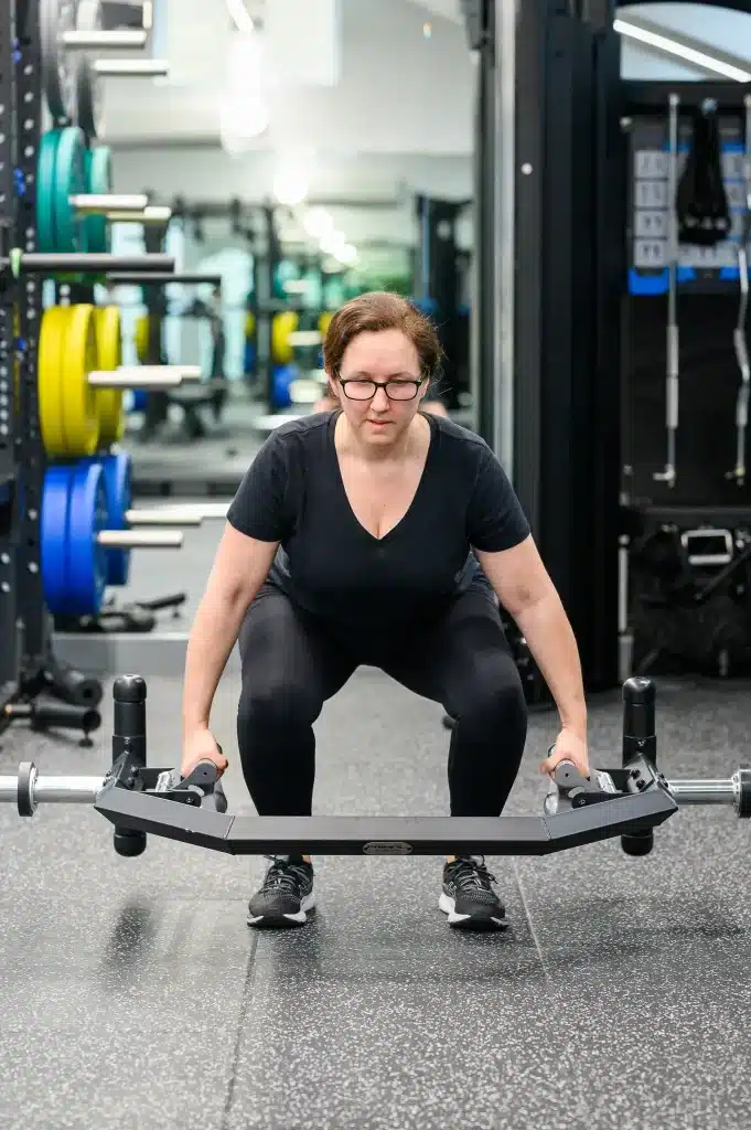 Photo of a woman performing a barbell deadlift in a well-equipped gym