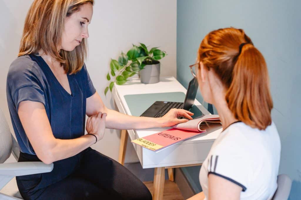 Photo of a women's health physiotherapist talking a patient through anatomy at a desk