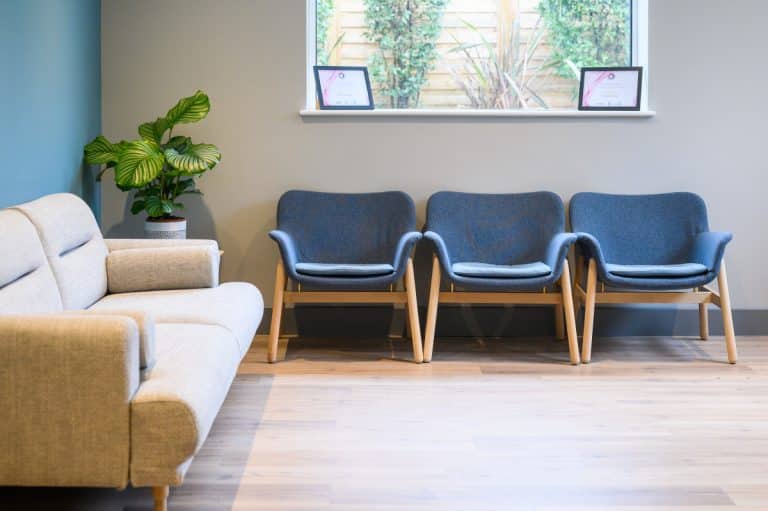 Photo of a calm Mint Wellbeing waiting room with a sofa, three armchairs, a plant and a window
