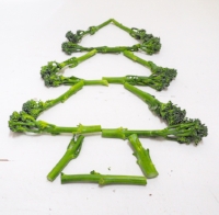 Christmas tree shape made from tenderstem broccoli on a white surface